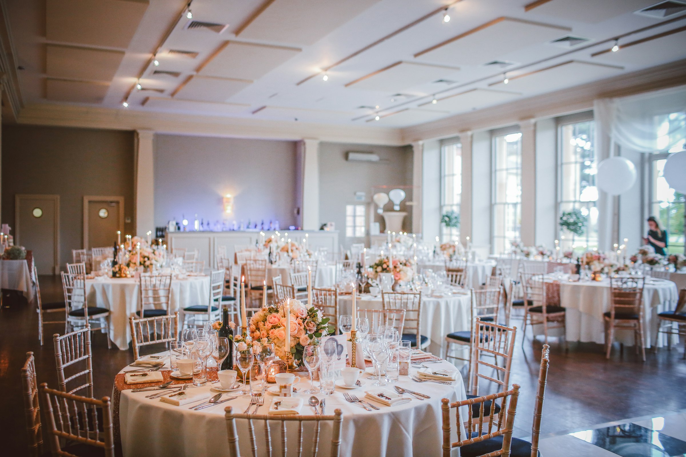 Banquet room laid with round tables and floral centrepieces